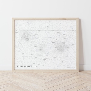 May include: A framed black and white topographic map of Sweet Grass Hills. The map shows contour lines and elevation changes.