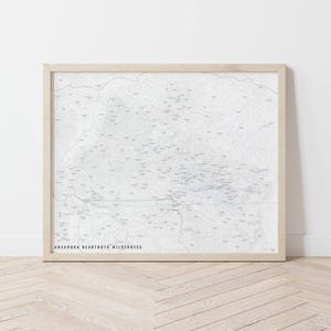 May include: A framed map of the Absaroka Beartooth Wilderness. The map is printed in black and white and shows the location of various trails and landmarks.