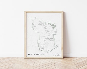 Puede incluir: Un mapa enmarcado del Parque Nacional Arches en Utah, con un fondo blanco y líneas negras que muestran los senderos y puntos de referencia del parque. El nombre del parque está impreso en negro en la parte inferior del mapa.