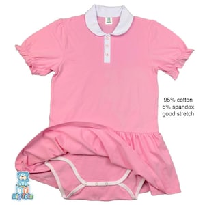 Peut inclure: Robe rose pour bébé avec un col blanc et des manches courtes à volants. La robe a une patte de boutonnage blanche avec trois boutons et un bas de jupe. Le texte sur l'image indique "95% coton 5% élasthanne bonne extensibilité". Logo Big Tots.