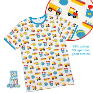 May include: White short-sleeved shirt with a blue trim and a pattern of colorful toy trucks, trains, boats, blocks, and balls. The shirt is made of 95% cotton and 5% spandex. The text "Big Tots" is visible on the bottom left.