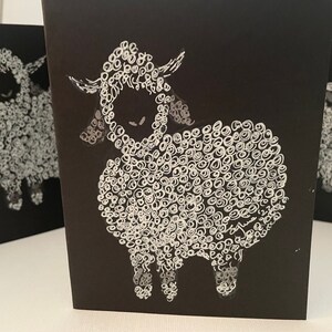 May include: A black card with a white illustration of a sheep. The sheep is drawn with a swirling pattern of white circles.