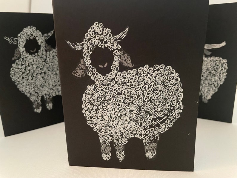 May include: A black card with a white illustration of a sheep. The sheep is drawn with a swirling pattern of white circles.