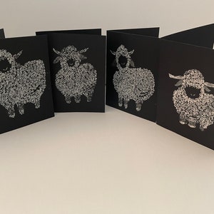 May include: Set of four black greeting cards with white illustrations of sheep. Each card features a different sheep design.