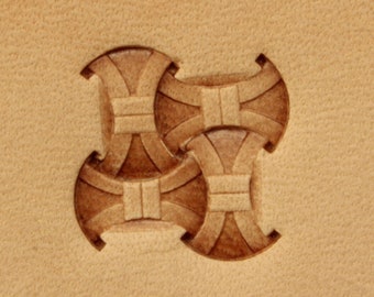 Könnte beinhalten: Nahaufnahme eines Lederstempels mit geometrischem Muster. Der Stempel ist aus braunem Leder gefertigt und hat ein erhabenes Muster aus vier sich überlappenden Kreisen.