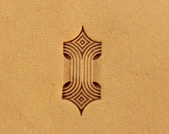 May include: A close-up of a leather surface with a decorative, geometric design embossed into it. The design is a stylized arrow shape with a series of concentric circles and squares.