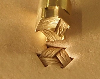 May include: A close-up of a leather crafting tool with a brass head and a metal shaft. The tool is used to create a decorative stitch pattern in leather.