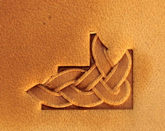 May include: A brown leather surface with a carved Celtic knot design in the corner.