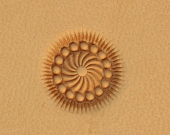 Può includere: Un primo piano di uno strumento di stampa in pelle con un design circolare che presenta un motivo a spirale circondato da un anello di punti.