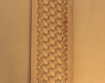 May include: A close-up of a piece of leather with a woven pattern and a decorative border. The leather is a light brown color.