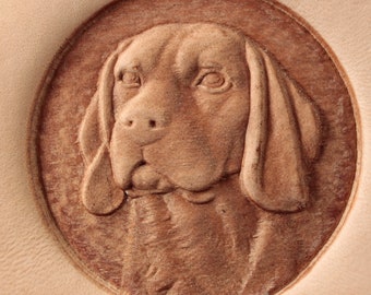 May include: A close-up of a leather carving of a dog's head. The dog has brown fur and floppy ears. The carving is detailed and realistic.