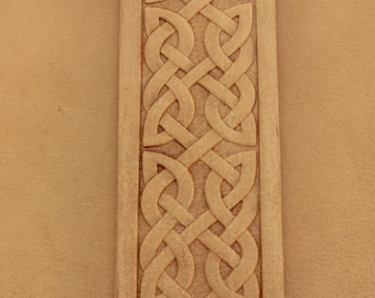 May include: A close-up of a brown leather surface with a detailed Celtic knot design carved into the surface.