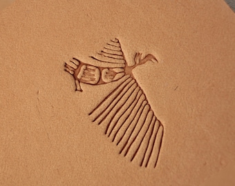May include: A close-up of a brown leather surface with a stylized image of a bird with outstretched wings. The bird is outlined in a darker brown color.