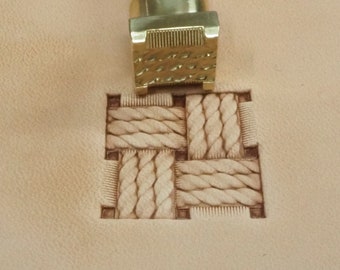 May include: A brass leather stamping tool with a rope design. The tool is being used to create an impression on a piece of leather.