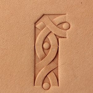May include: A close-up of a leather carving with a Celtic knot design. The carving is in a light brown color and has a textured surface.