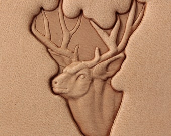 May include: A detailed leather carving of a deer head with large antlers. The carving is done in a light brown color and is set against a tan background.