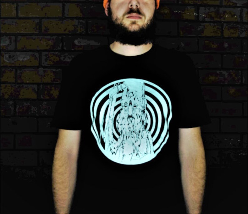 May include: A black t-shirt with a glow-in-the-dark design of a face with a spiral pattern around it.