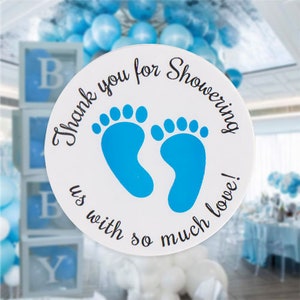 May include: Round white sticker with blue baby footprints and the text "Thank you for showering us with so much love!"