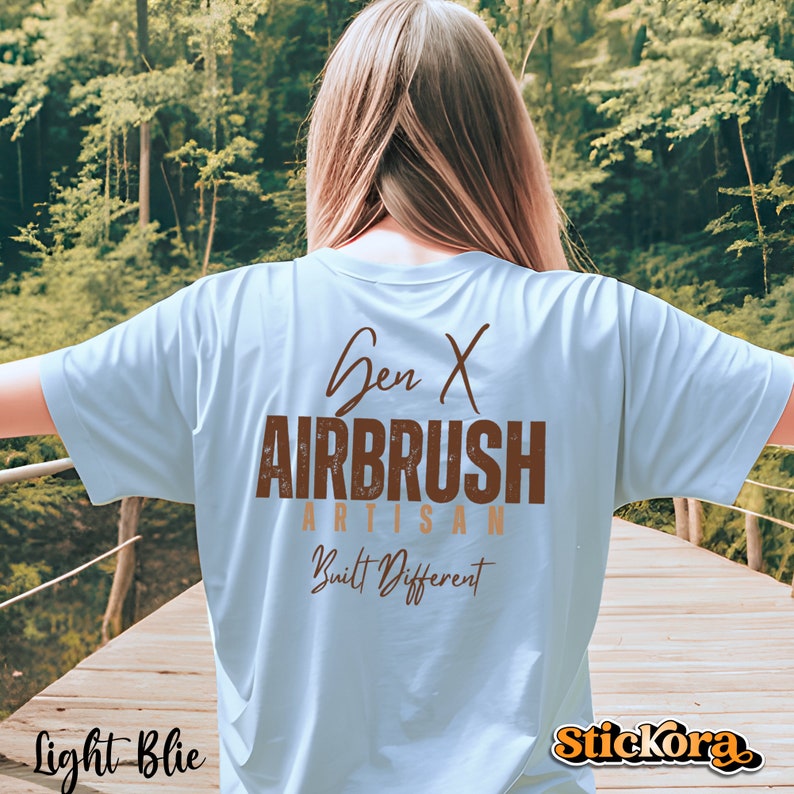 May include: Light blue t-shirt with brown text that reads "Gen X Airbrush Artisan Built Different".