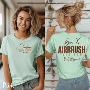 May include: A mint green t-shirt with a brown graphic that says "Christine Glow Dealer Est 2023" on the front and "Gen X Airbrush Artisan Built Different" on the back.