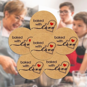 May include: Six brown round stickers with the text "baked with love" and a red heart in a mitten design.
