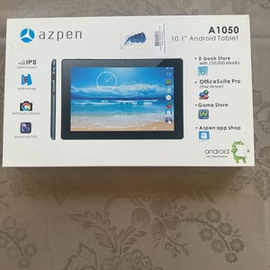 May include: A white rectangular box for an Azpen A1050 10.1 inch Android tablet. The box features an image of the black tablet displaying a beach scene, along with icons for IPS screen, 16GB storage, 2MP dual cameras, and a quad core CPU.