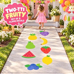 May include: A set of eight fruit-themed floor decals featuring a pineapple, banana, grapes, pear, strawberry, watermelon slice, lemon, and blueberries. The text TWO-TTI FRUITY SET OF 8 FLOOR DECALS is displayed in a pink cloud-shaped graphic.