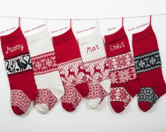 May include: Six red and white Christmas stockings with different designs and names embroidered on them. The stockings are hung on a white background.