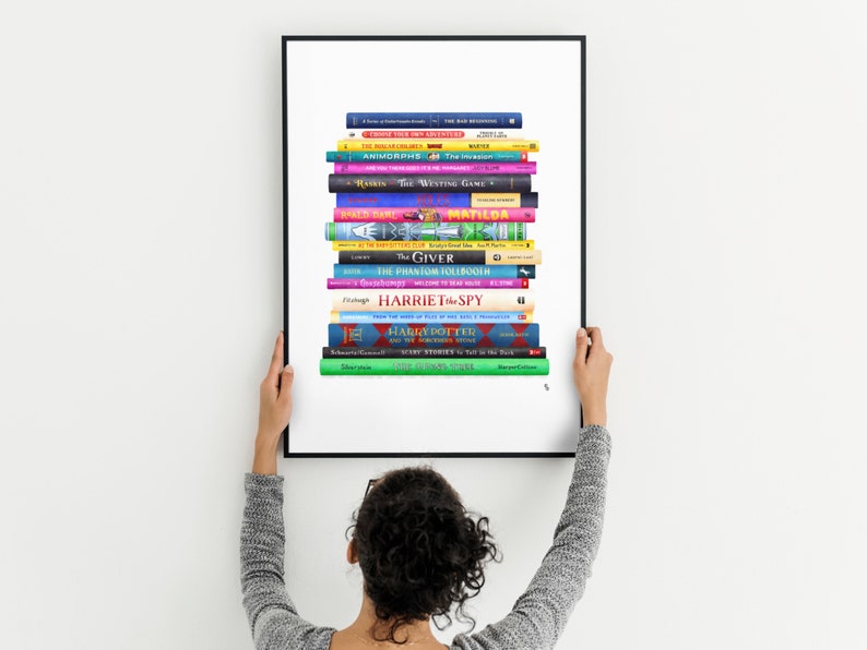 May include: A framed print of a stack of colorful books, including titles like "The Giver", "Matilda", "The Phantom Tollbooth", and "Harriet the Spy".