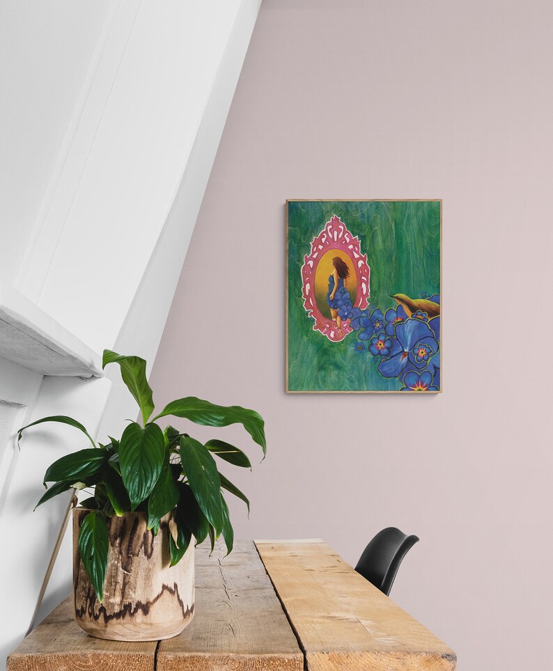 May include: A framed painting of a woman in a blue dress standing in a pink ornate mirror with blue flowers on a green background.