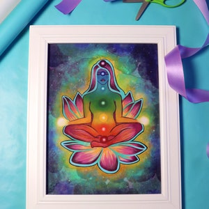May include: A framed painting of a woman meditating in a lotus position with a rainbow aura. The woman is surrounded by a galaxy background with stars and nebulae.