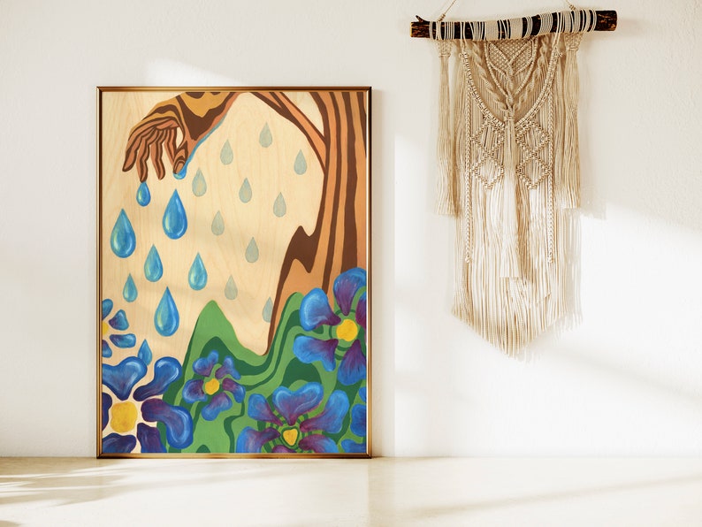 Puede incluir: Una pintura sobre un panel de madera que representa una mano que se extiende desde un &aacute;rbol, con gotas de lluvia azules que caen de la mano y el &aacute;rbol. El fondo es de color madera claro con flores azules y verdes en la parte inferior.