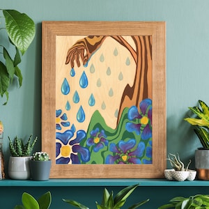 Puede incluir: Una pintura enmarcada con una mano estilizada que vierte gotas de lluvia azules sobre un paisaje de colinas verdes y flores azules.