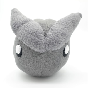 以下が含まれることがあります： グレーのぬいぐるみで、2本の大きな角と白い目があります。おもちゃは丸いしずくの形をしています。