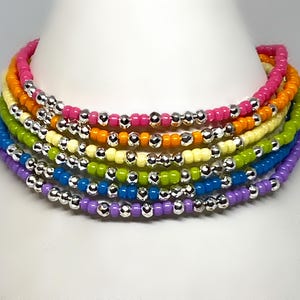May include: A multi-colored beaded bracelet with alternating silver beads. The bracelet is made of a variety of colors, including purple, blue, green, yellow, orange, and pink.