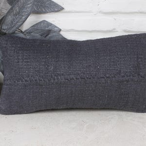 May include: A dark grey woven cushion with a textured surface. The cushion is rectangular and has a subtle pattern.