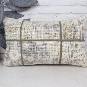 May include: A rectangular cushion with a patchwork design in shades of beige and white. The cushion is made from a woven fabric with a subtle texture. The cushion has a simple, elegant design that would complement a variety of home decor styles.