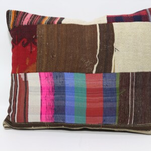 Può includere: Una federa patchwork con una varietà di colori e motivi, tra cui rosso, marrone, bianco, rosa, blu e verde. La federa è realizzata in tessuto tessuto e ha un bordo marrone.