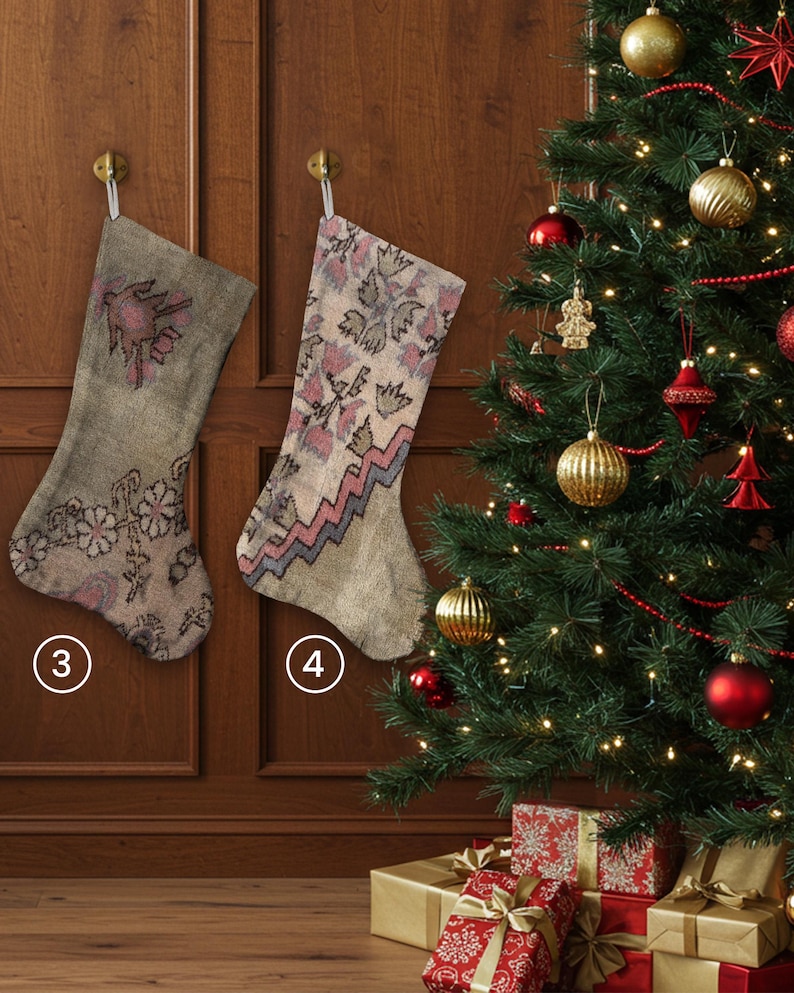 Pu&ograve; includere: Due calze di Natale con motivi floreali e geometrici sono appese a una porta di legno. Le calze sono nei toni del beige, rosa e grigio. Sullo sfondo, un albero di Natale decorato con ornamenti e regali confezionati.
