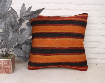 May include: A striped throw pillow with orange, black, and red stripes. The pillow is made of a woven fabric and has a soft, textured feel.