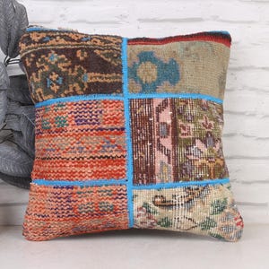 May include: Square patchwork pillow with a variety of colors and patterns. The pillow features a mix of textures and designs, including floral and geometric motifs. The edges are outlined with a bright blue trim. A decorative accent for a sofa or bed.
