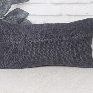 Può includere: Un cuscino da lancio grigio scuro con una trama tessuta. Il cuscino è realizzato in un materiale morbido e confortevole ed è perfetto per aggiungere un tocco di stile a qualsiasi stanza.
