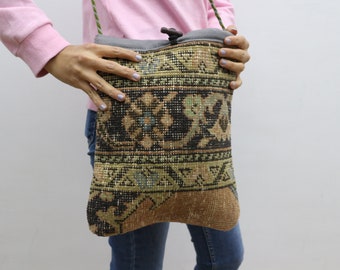 May include: A brown and black patterned crossbody bag with a green strap. The bag is made from a woven fabric and has a flap closure.