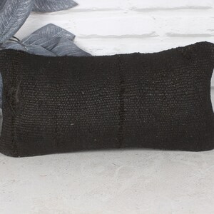 May include: Black woven throw pillow with a textured surface.
