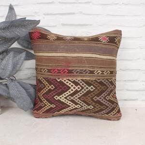 May include: A brown and beige patterned throw pillow with a geometric design. The pillow has a woven texture and is made of a soft, comfortable fabric.