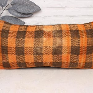May include: Orange and brown checkered throw pillow with a woven texture.