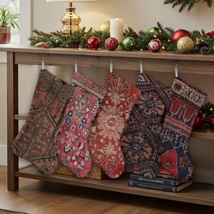Puede incluir: Cinco calcetines navideños con intrincados y coloridos diseños cuelgan de una estantería de madera decorada con guirnaldas, adornos y una lámpara. Los calcetines tienen un aspecto vintage, similar a una alfombra, con tonos rojos, azules y marrones.