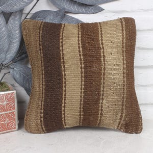 May include: A brown and beige striped throw pillow with a woven texture. The pillow is made of a soft, natural material and has a rustic look.