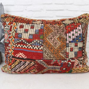May include: Rectangular patchwork pillow with a vibrant mix of colors and patterns. The pillow features a combination of red, orange, blue, and white geometric designs. The pillow is a decorative item for a bed or sofa.