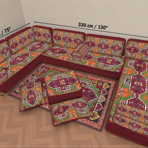 Può includere: Un divano componibile con un motivo rosso, verde e arancione. Il divano è lungo 330 cm, largo 190 cm e profondo 70 cm. Include cuscini abbinati e un tappeto con un design simile.